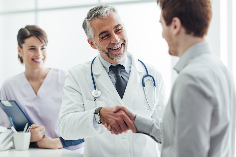 Smiling doctor shaking hands with patient